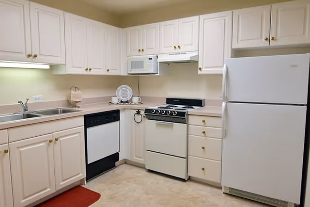 U-shaped kitchen with white cabinets and white appliances including a refrigerator, stove, microwave and dishwasher.