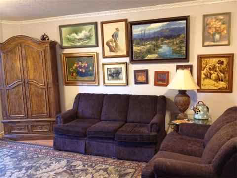 Cozy living room with brown sofa set, armchairs, and framed wall art.