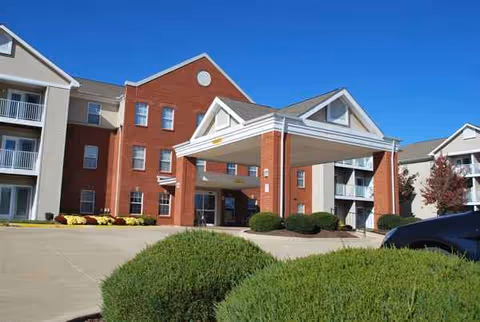 Front view of a brick senior living facility with a covered entrance and manicured landscaping.