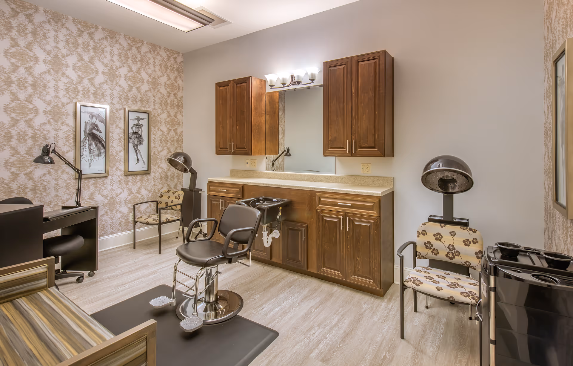 Interior salon room with styling chairs, a hair-washing sink, hood dryer, wooden cabinets and seating.