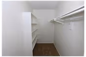 Walk-in closet with built-in shelves on the left and hanging rods on the right.