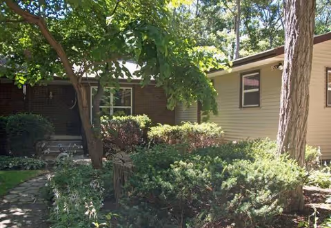 Exterior view of Lang Home with trees, shrubs, and a walkway in front of the building.