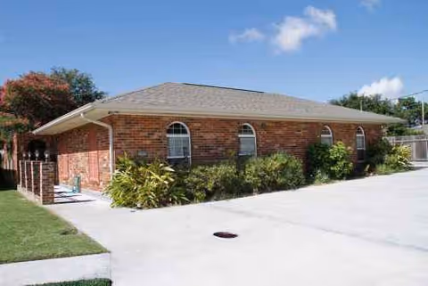 Brick senior residence building with arched windows and a paved driveway.