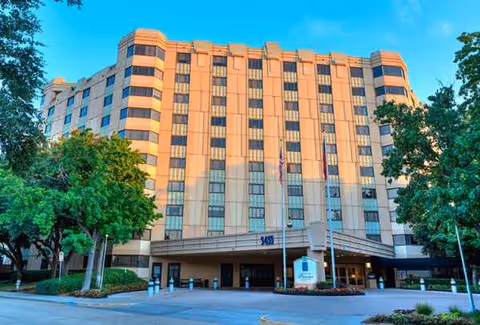 Exterior facade of a tall beige senior living building with a covered entrance