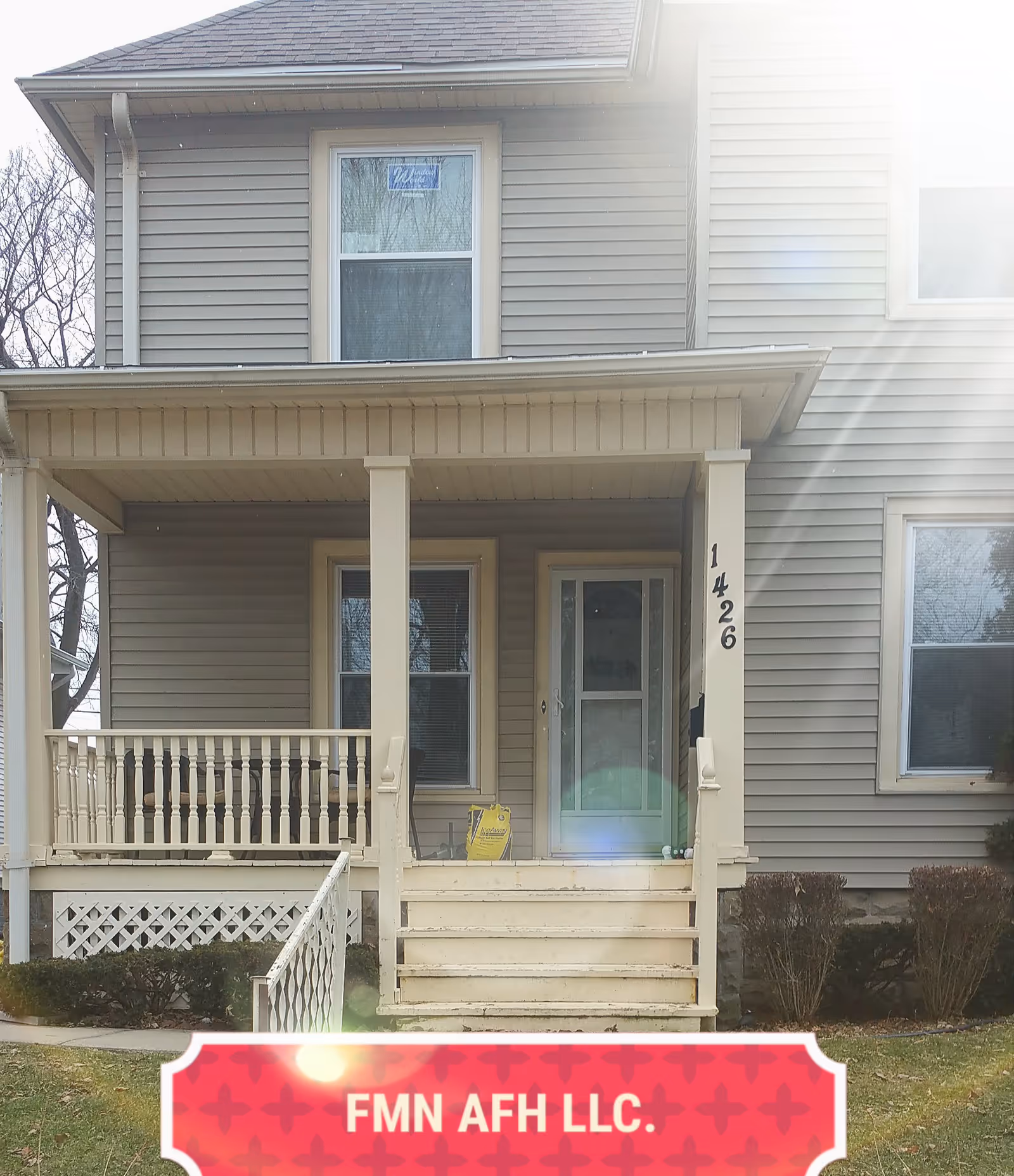 Front porch and entrance of a two-story house with steps, a railing, house number 1426, and a red banner reading "FMN AFH LLC."