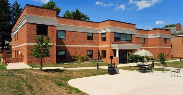 Exterior view of Hughes Home, Inc., a brick building with front entrance and outdoor seating.