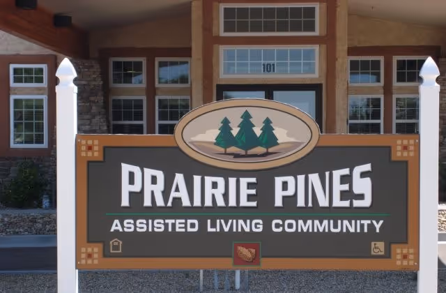 Large sign reading "Prairie Pines Assisted Living Community" standing in front of the building entrance.
