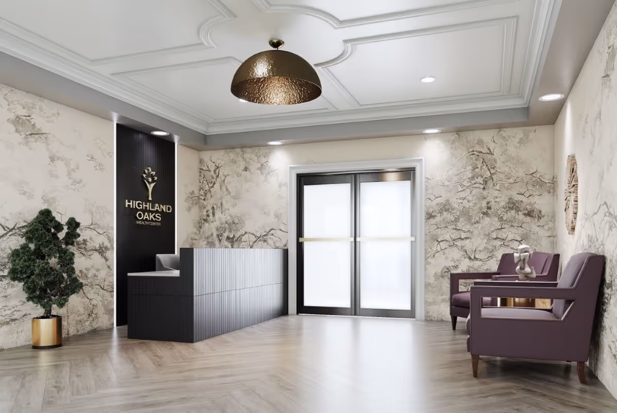 Reception area of Highland Oaks Health Center featuring a modern black reception desk, a potted plant in a gold planter, two purple armchairs with a small table between them, and double frosted glass doors. The walls have a textured design resembling tree branches, and a large bronze pendant light hangs from the ceiling.