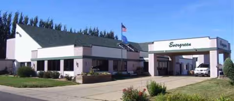 Exterior view of Evergreen senior living facility with entrance, driveway, and landscaping.