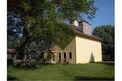 Front view of a yellow two-story building with a porch and green lawn.