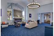 Spacious communal living room with sofas and chairs arranged around a stone fireplace beneath a large chandelier.