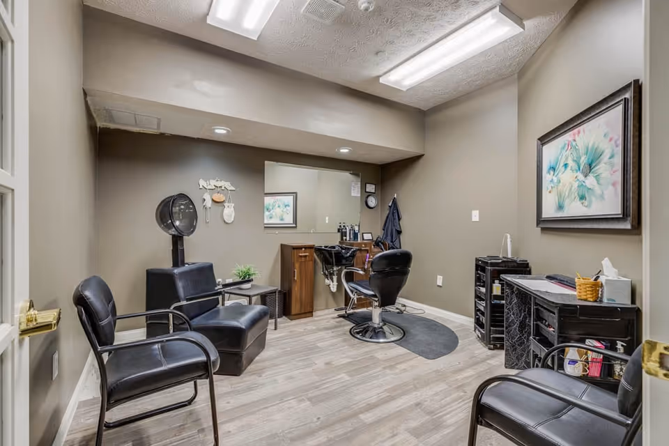 Small salon/styling room with salon chairs, a hooded hair dryer, a styling station and a mirror.