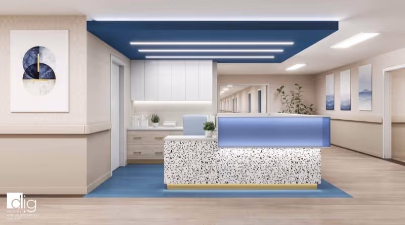 Reception area in a healthcare and rehabilitation center with a modern desk featuring a terrazzo front panel and blue illuminated top. Behind the desk are white cabinets and drawers, a small plant, and a water pitcher. The ceiling above the desk has blue panels with linear lights. The hallway extends to the right with framed artwork and plants along the walls.