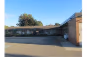 Single-story brick senior living building with driveway and blue sky.