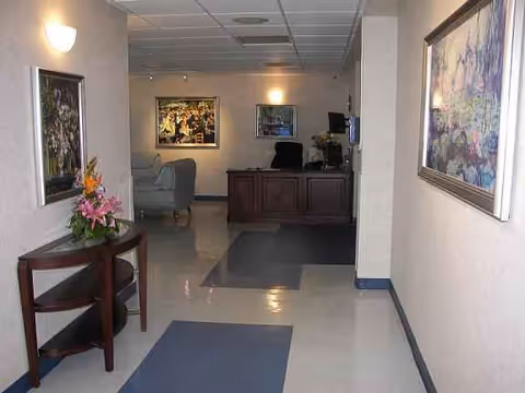 Nursing facility lobby with a reception desk, seating, and framed artwork.