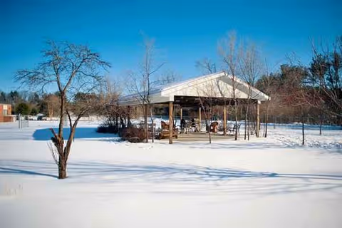 Snowy outdoor pavilion with seating under a shelter at Wild Rose Manor.