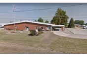 Single-story brick care center exterior with driveway, flagpole, and manicured lawn