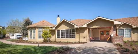 Single story beige senior living facility with a covered entryway and large front windows.