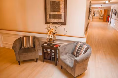 A quiet hallway seating area with two gray armchairs, a small table, and decor.