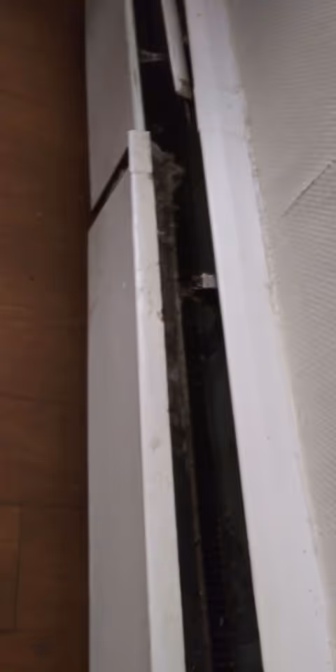 Narrow view of a broken white cabinet drawer exposing dark interior.
