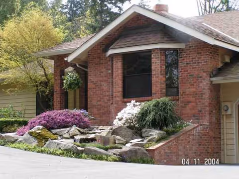 Brick senior living facility exterior with landscaped rock garden and visible date stamp.