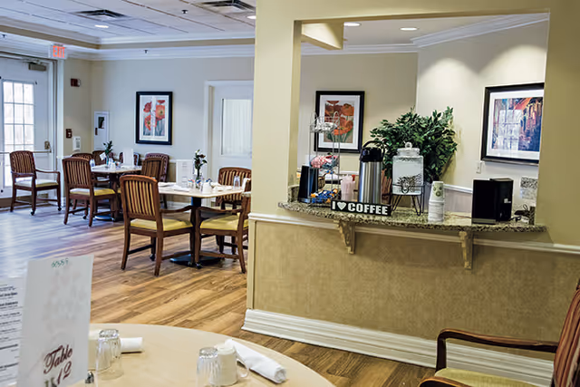 Dining room with wooden tables and chairs and a self-serve coffee station on a counter