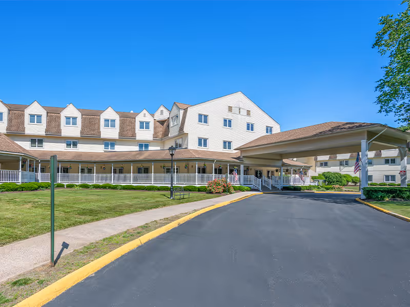 Exterior view of Holiday Farmington senior living facility with a long covered entrance and driveway.