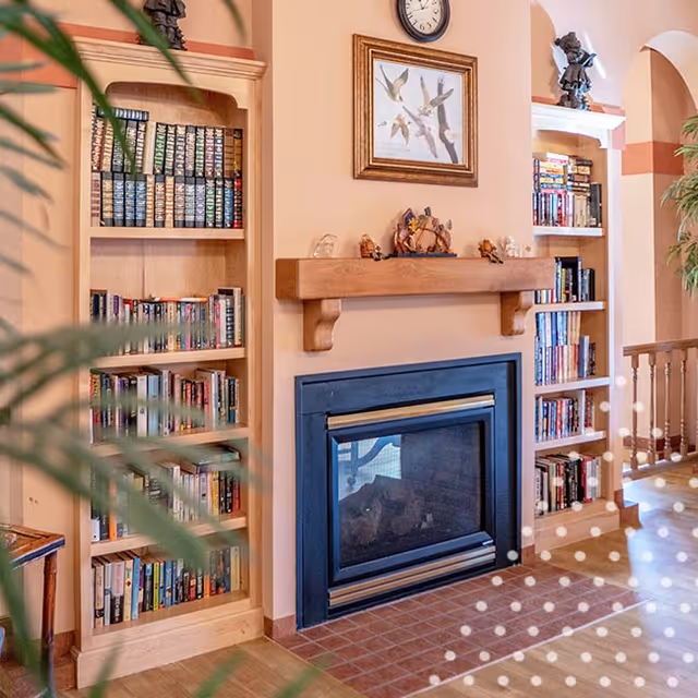 Cozy living area featuring a fireplace with a wooden mantel flanked by built-in bookshelves.