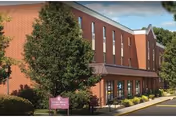 Exterior view of Seneca Senior Living building with red brick facade, trees, and entryway.