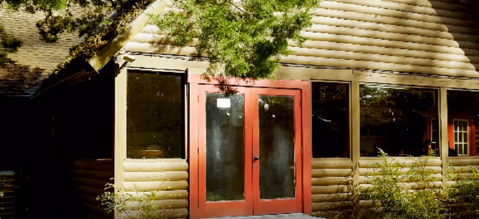 Front view of Homewood Lodge ALF entrance with red doors and beige siding.
