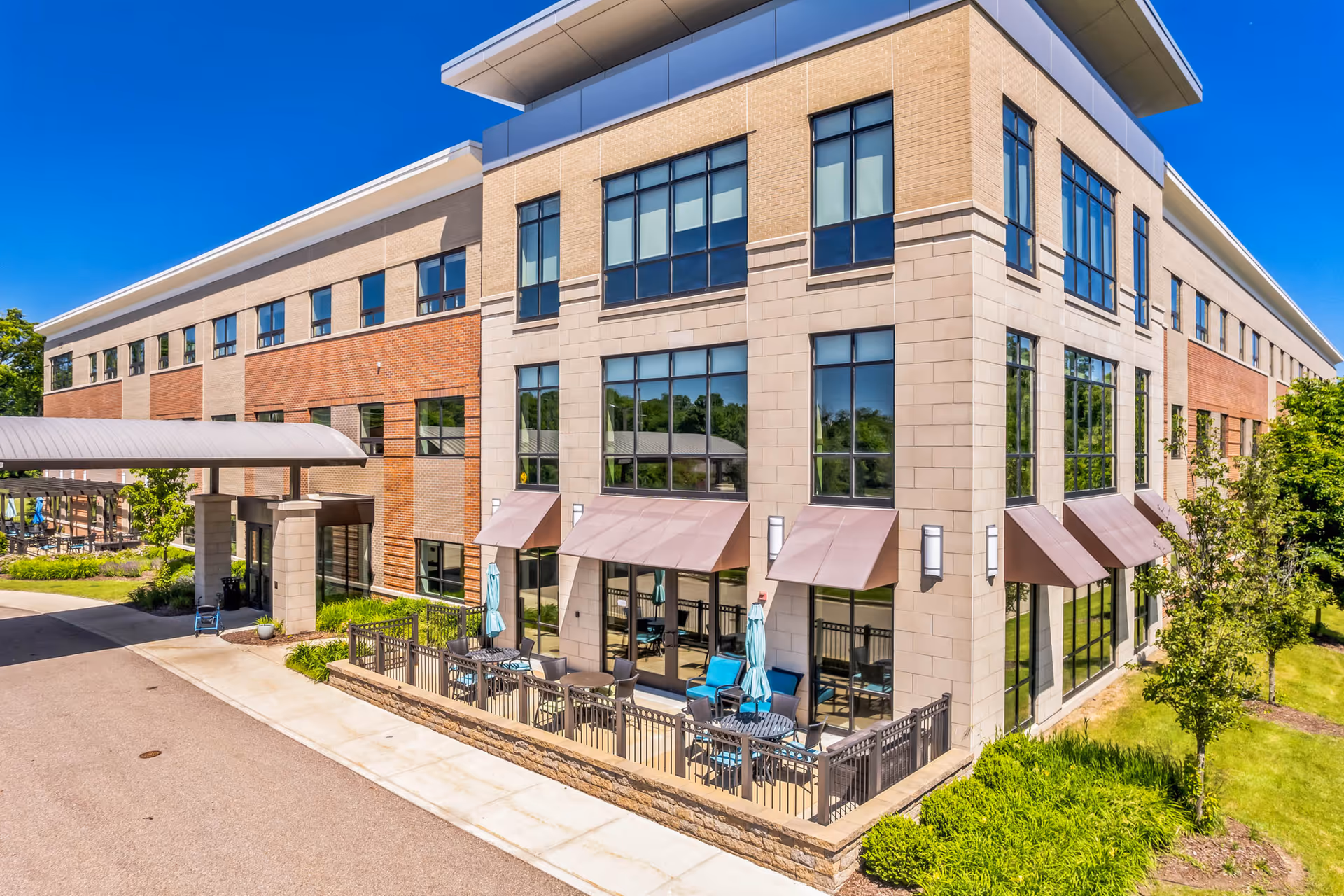 Exterior view of a modern three-story Willowbrook Hills building with an outdoor patio and covered entrance.