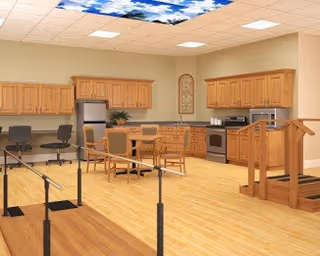 Spacious interior common room with a kitchenette, wooden cabinets, a small dining table and chairs, and parallel bars for rehabilitation.