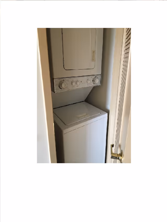 Stacked washer and dryer unit inside a small closet with a louvered door.