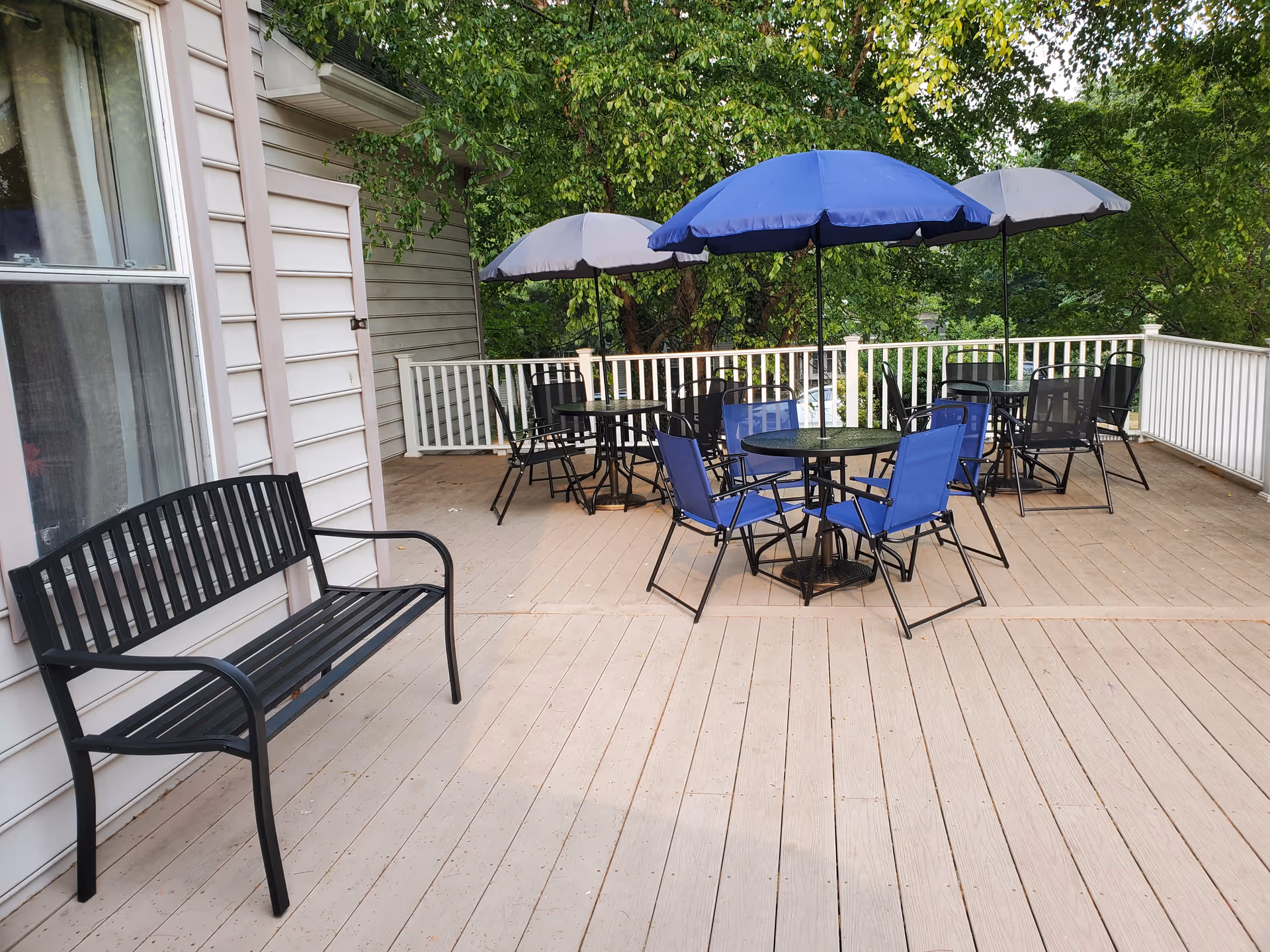 Outdoor deck at Rolling Meadows Assisted Living with tables, chairs, and umbrellas.