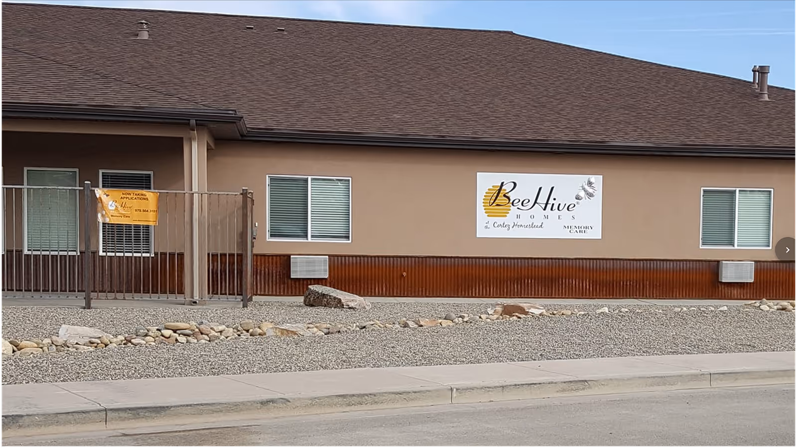Exterior front of a single-story BeeHive Homes at the Cortez Homestead building with visible signage and gravel landscaping.