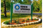 A green-framed roadside sign reading "Eden Springs Nursing & Rehab Center" set in a landscaped lawn.
