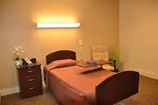 A small bedroom in a senior living facility featuring a single bed and nightstands.