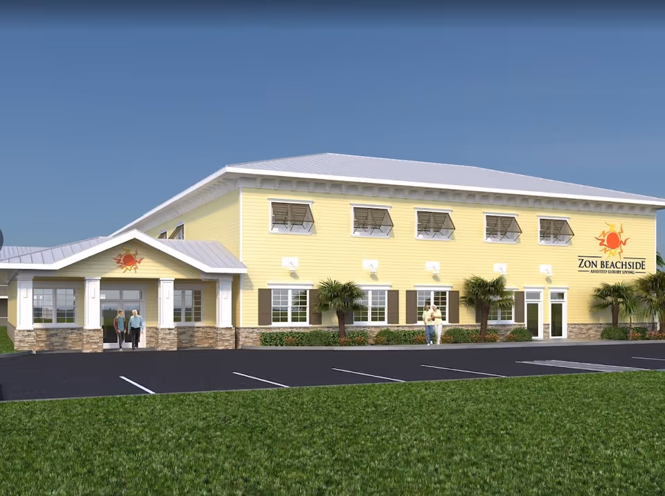 Front exterior of a yellow two-story Zon Beachside assisted living building with a parking lot, palm trees, and people near the entrance.