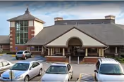 Exterior view of Bayview Rehabilitation at Scalabrini showing the main entrance with a covered drop-off area. Several cars are parked in front of the building under a partly cloudy sky.