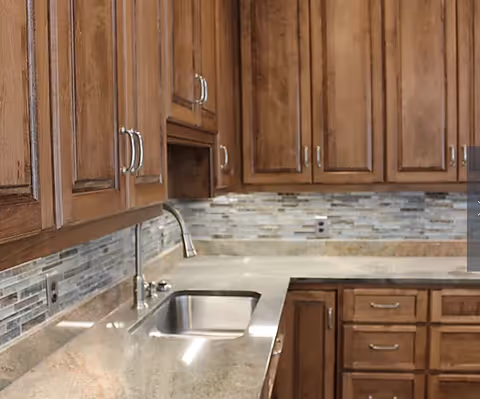 Kitchen with granite countertops, a stainless steel sink, mosaic tile backsplash, and wooden cabinets.