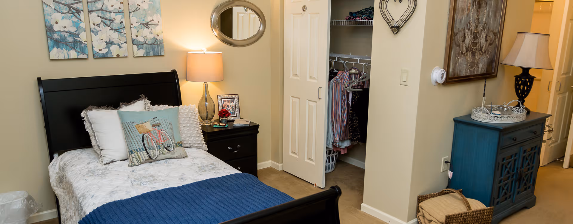 A cozy furnished bedroom with a bed, nightstand, open closet, and dresser.
