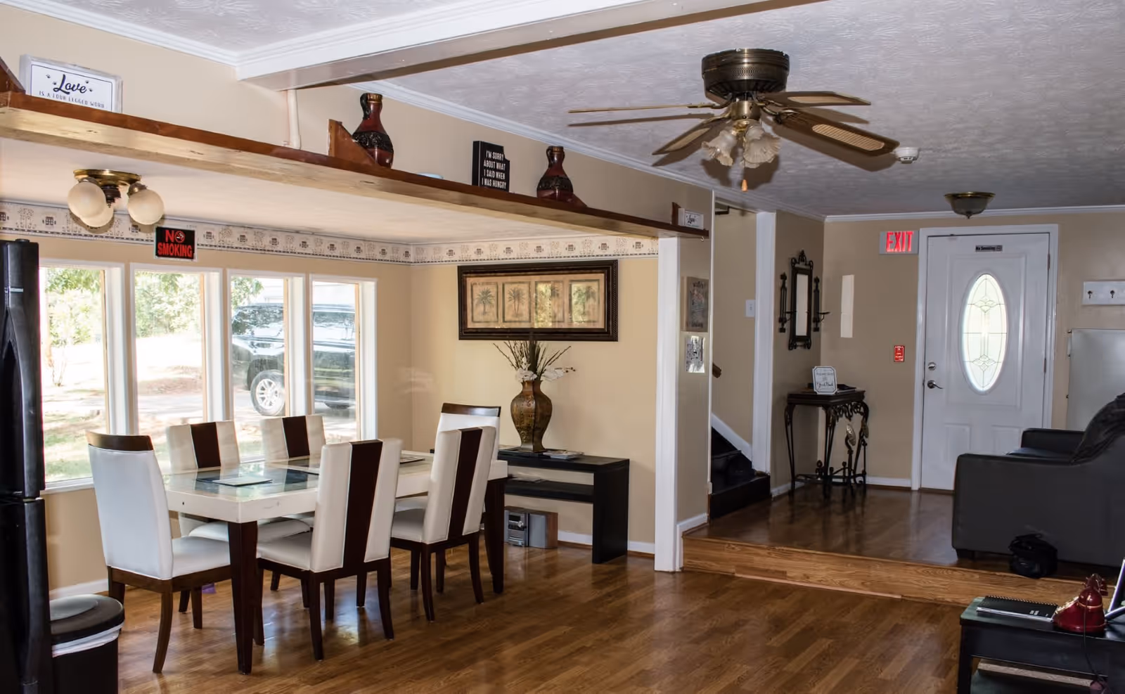 Open-plan interior with a dining table and six chairs by windows, a living area with sofa, and an entry door.