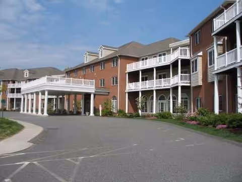 Brick senior living building with covered entrance, balconies, and a curved driveway.