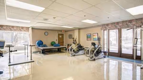 Interior fitness room with stationary bikes, mats, and large windows.