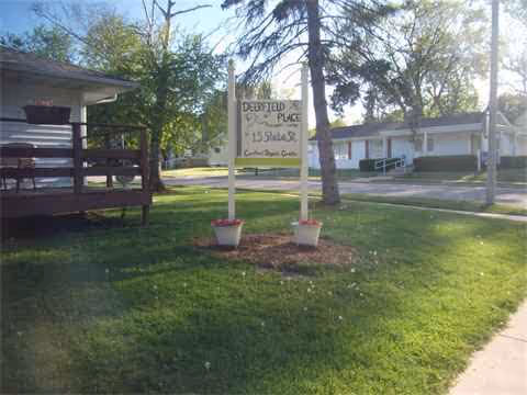 Exterior view of Deerfield Place Assisted Living sign by the building and lawn