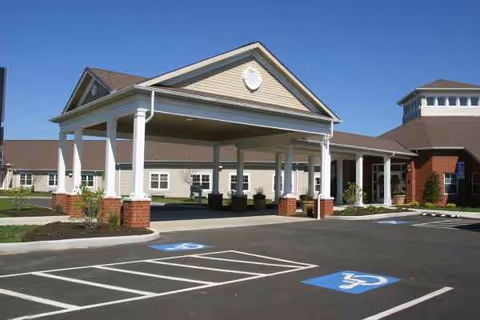 Exterior view of a senior living facility entrance with a covered drop-off and handicap parking.