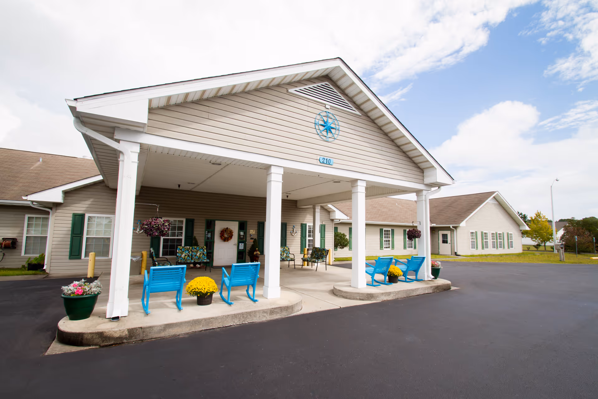 The front entrance of Croatan Ridge Rehabilitation & Nursing Center featuring a covered porch with blue chairs and flower pots.