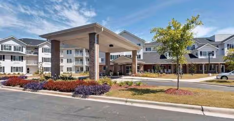 Shads Landing retirement community exterior with a covered entrance, manicured landscaping, and a driveway.
