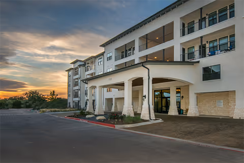 Exterior view of a multi-story senior living building with a covered entrance and parking area.