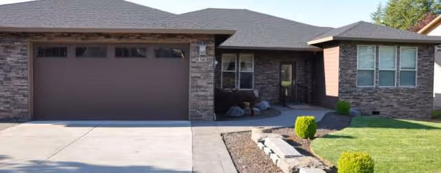 Front exterior of a single-story brick house with a two-car garage and tidy lawn.